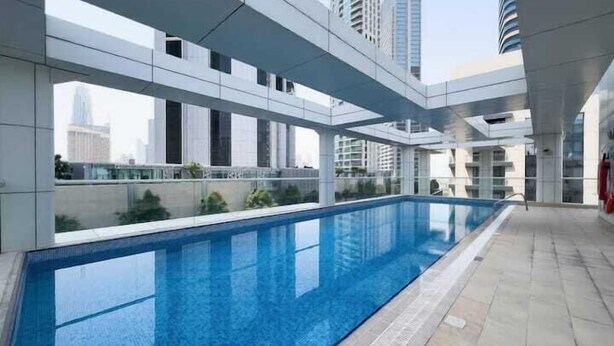 A modern building with a long swimming pool, large windows, and a view of the city skyline. - Vogue | Mon Reve Downtown near Dubai Mall | Burj Khalifa (Dubai)