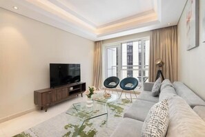 Departamento de lujo, balcón, vista a la ciudad | Área de sala de estar | Smart TV de 65 pulgadas con canales por cable 