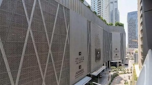 A modern building with a unique geometric facade, featuring a pattern of intersecting lines and a prominent advertisement for Aliexpress. - Vogue | Mon Reve Downtown near Dubai Mall | Burj Khalifa (Dubai)