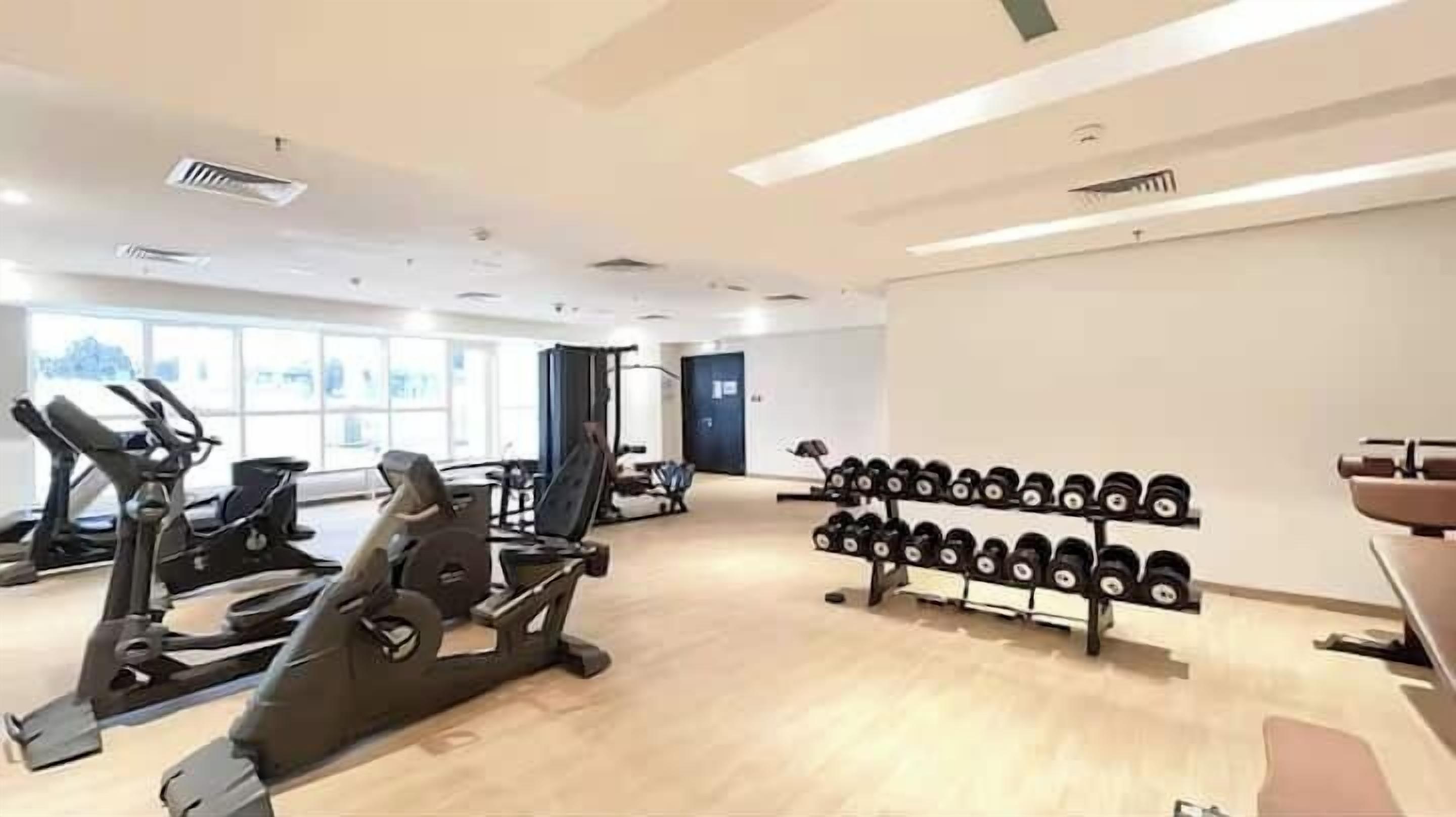 A gym with cardio machines, weight racks, and a large window.