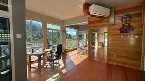 A spacious room with large windows, a wooden floor, a desk with a chair, and an air conditioning unit. - Exclusive 2 Bed Mountain & Farm Villa Escape (Spring Garden)