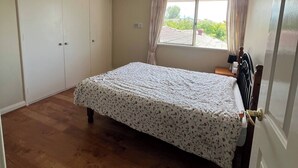 A bedroom with a bed, a ceiling fan, a window with curtains, and a radiator. - Room-executive Style Stay, Fast Wi-fi, p (Perth)