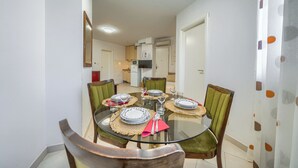 Un comedor con una mesa de vidrio, cuatro sillas y una cocina al fondo.
