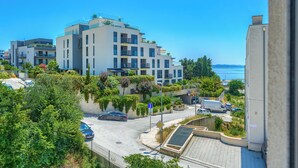 Un moderno edificio de apartamentos con balcones, zona de estacionamiento y vistas al mar.