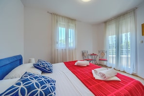 A hotel room with a bed, two chairs, a small table, and large windows with sheer curtains. - A Comfortable apt w Balcony, 4 min Walk to Beach (Split)