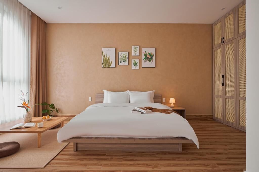 A modern bedroom with a large bed, a bedside table with a lamp, and a window with curtains.