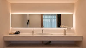 A modern bathroom with a large mirror, a white sink, and a vase with flowers. - Yen Stay and Coffee (Xuan Huong - Da Lat)