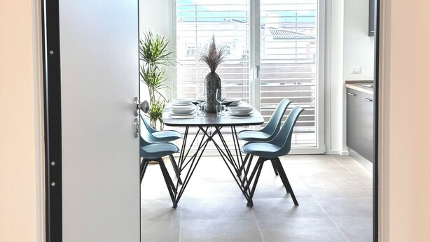 Een moderne eetruimte met een glazen scheidingswand, een tafel met stoelen en uitzicht door de wand.