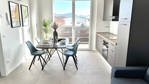 Een modern appartement met een eethoek, kitchenette en een balkon met uitzicht over de stad.