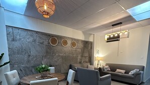 Una sala de estar moderna con una mesa redonda de madera, sofás grises y un techo con tragaluces.