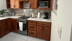 Una cocina con armarios de madera, una estufa a gas, un microondas y un tostador.