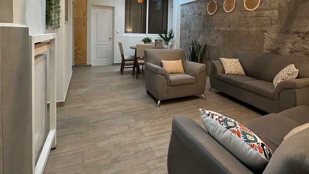 Una sala de estar moderna con un sofá, un sillón y un comedor con una mesa y sillas.