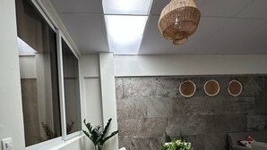 Un comedor con una mesa redonda de madera, cuatro sillas, una lámpara colgante de fibras y una pared de piedra con adornos circulares.