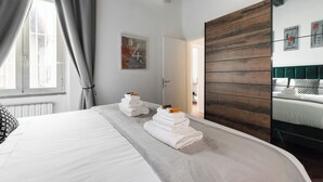 Een hotelkamer met een groot bed, een wand van houten panelen, een spiegel en een raam met gordijnen.