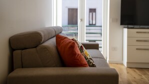 Ein modernes Wohnzimmer mit einer Couch, einem Fernseher und Blick auf ein Gebäude.