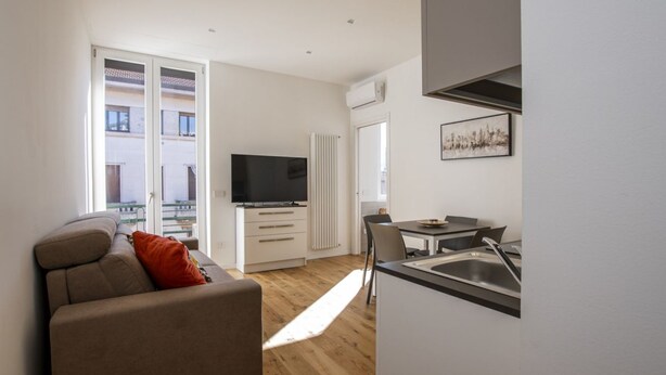 Eine moderne Wohnung mit Wohnbereich, Küchenzeile und einem Balkon.