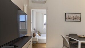 Eine moderne Küche mit einem großen Herd, ein Essbereich mit Tisch und Stühlen sowie ein Schlafzimmer mit Bett und Fenster.