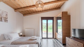 A bedroom with two beds, a wooden ceiling, a TV, and a view through a glass door. - Altura Villa,Private Pool , one storey , for Up to 7 geusts (Saitoures)