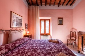 Ein Schlafzimmer mit Bett, Fenster, Stuhl, Schrank und einem Bild an der Wand.