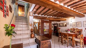 Un interior rústico con una escalera, una mesa de comedor de madera y un jarrón de flores.