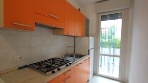 Una cocina con gabinetes naranja, una estufa a gas y una ventana con vista a la vegetación.