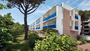 A multi-story building with a modern architectural design, featuring balconies and a garden area. - Duplex 100mt from the beach (Bibione Pineda)