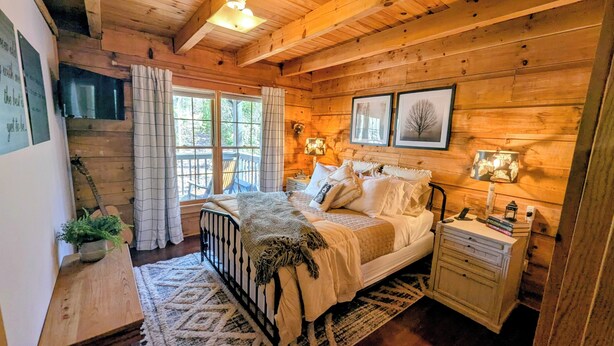 Een gezellige blokhut slaapkamer met een bed, nachtkastjes en een raam met gordijnen.