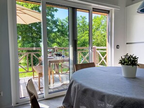 Ein Zimmer mit einer Schiebetür zu einer Terrasse, einem runden Tisch mit Tischdecke und einer Topfpflanze.