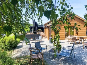Eine Holzhütte mit Sitzgelegenheiten im Freien und einer Schotterterrasse.