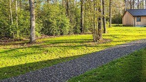Ländliche Landschaft mit einem Schotterweg, einer Holzhütte und einem bewaldeten Gebiet.