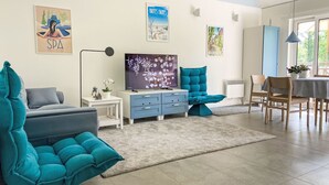 Ein modernes Wohnzimmer mit türkisfarbenen Sofas, einem Flachbildfernseher und Kunstwerken an den Wänden.