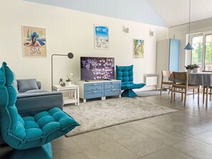 Ein modernes Wohnzimmer mit Türkis-Sofas, einem Flachbildfernseher und Kunstwerken an den Wänden.
