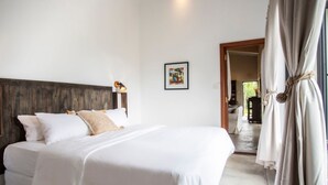 Een slaapkamer met een groot bed, een houten hoofdbord, een nachtkastje met een lamp en een ingelijste foto aan de muur.
