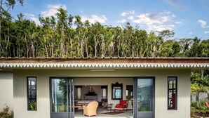 Een modern huis met een overdekt terras, grote ramen en een weelderige tuin.