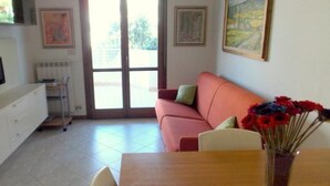 Un soggiorno con divano, tavolo da pranzo e TV a parete.