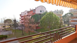 A residential building with balconies, a garden area, and a view of other buildings. - Cozy flat for four guests just steps from the sea (Grado)