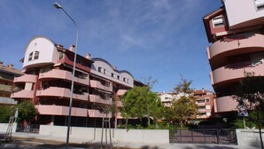 A multi-story residential building with balconies and a curved roof design. - Cozy flat for four guests just steps from the sea (Grado)
