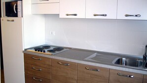 Une cuisine moderne avec des armoires blanches, un évier en acier inoxydable et une cuisinière intégrée.