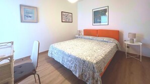 Une chambre à coucher avec un lit, deux tables de chevet, une chaise et des œuvres d’art accrochées aux murs.