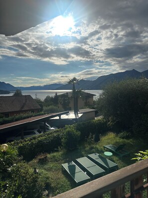 Een uitzicht op een huis met een terras dat uitkijkt over een meer en bergen.