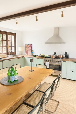 A kitchen with a wooden table, chairs, a stove, and a sink. - Above the Lake (Colmegna)