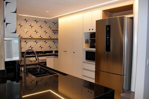 Eine moderne Küche mit einem Edelstahl-Kühlschrank, einem eingebauten Backofen und einer eleganten schwarzen Arbeitsplatte.