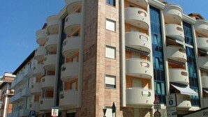 A multi-story hotel with balconies, a sign for a restaurant, and a parking sign. - Family friendly vacation apartment with a balcony (Grado)