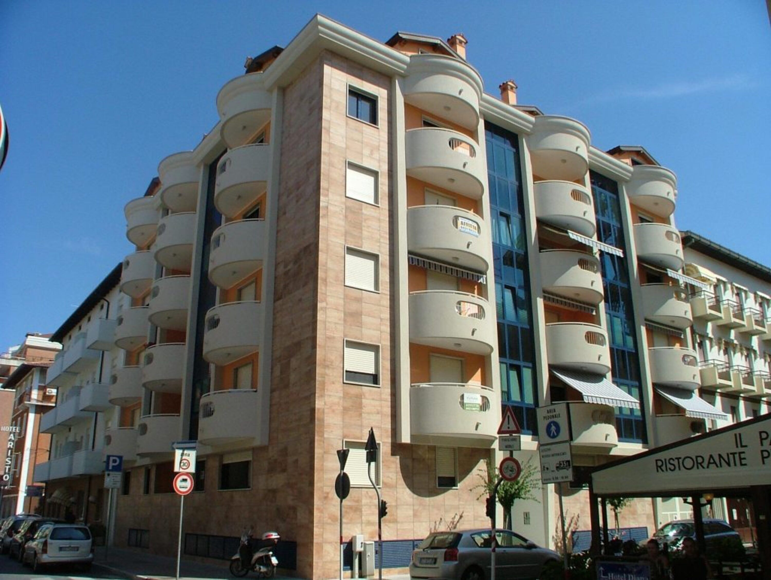 A multi-story hotel with balconies, a parking sign, and a restaurant sign.