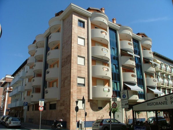 A multi-story hotel with balconies, a parking sign, and a restaurant sign.