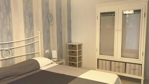 Een slaapkamer met een bed, een kledingkast, een nachtkastje en een muur met verticale strepen.