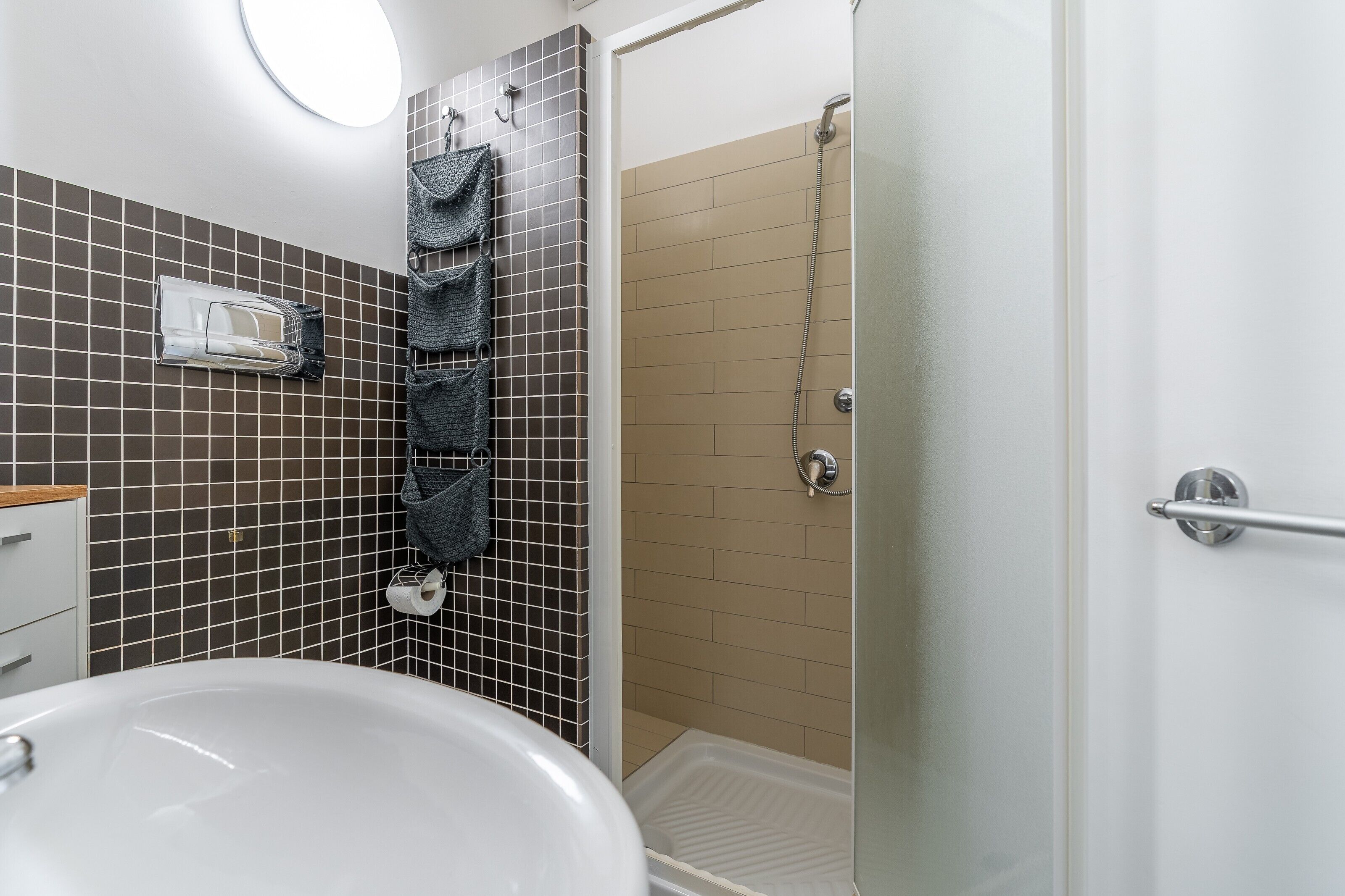 Une salle de bain avec un lavabo blanc, une cabine de douche en verre et un porte-serviettes avec plusieurs serviettes.