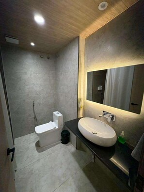 Egy modern fürőszoba, amelyben WC, mosdókagyló és zuhanyzó található.