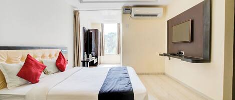 A modern hotel room with a large bed, a flat-screen TV mounted on the wall, and an air conditioning unit.