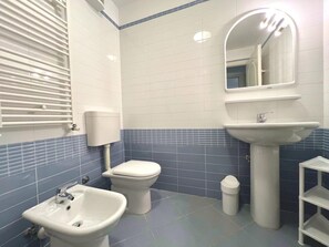 Une salle de bain équipée de toilettes, d’un bidet, d’un lavabo et d’un miroir.